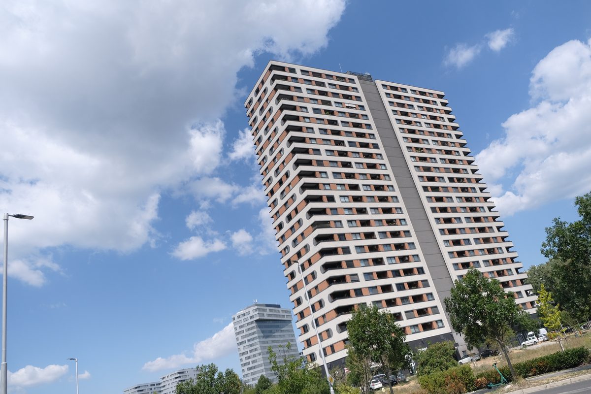 A tall residential tower block against a cloudy sky
